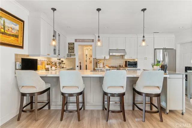 a kitchen with stainless steel appliances kitchen island granite countertop a table chairs and a wooden floor