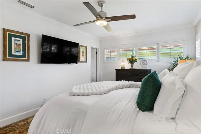 a bedroom with a bed a flat screen tv and a large window