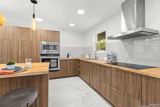 a kitchen with stainless steel appliances kitchen island granite countertop a sink dishwasher a stove a refrigerator a microwave oven with white cabinets and wooden floor