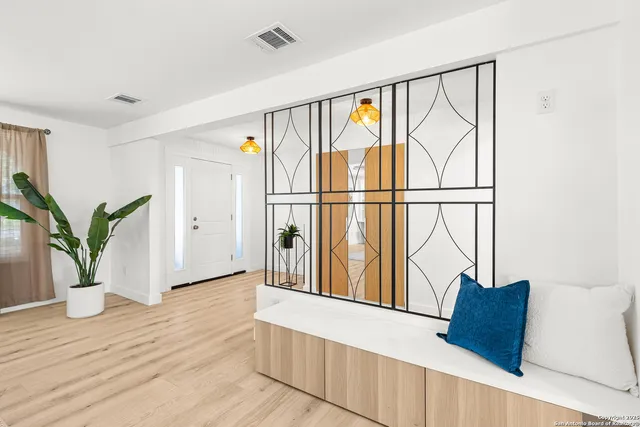 a view of an empty room with wooden floor and a potted plant