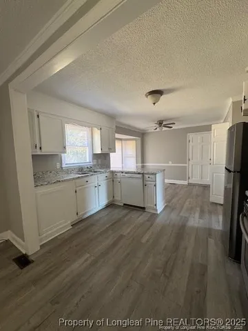 a view of a kitchen with refrigerator and white cabinets