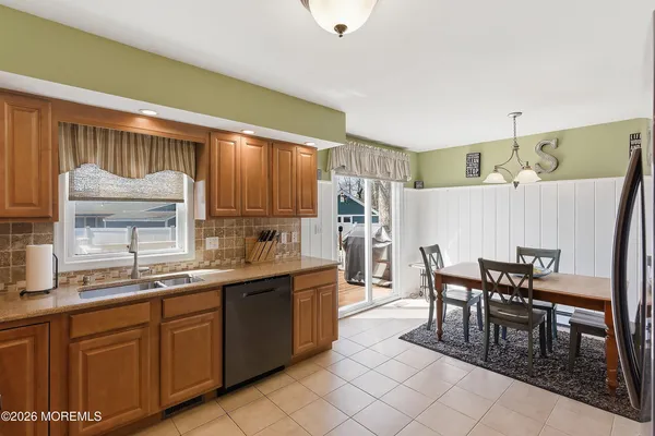a kitchen with cabinets a sink dishwasher a dining table and chairs with wooden floor
