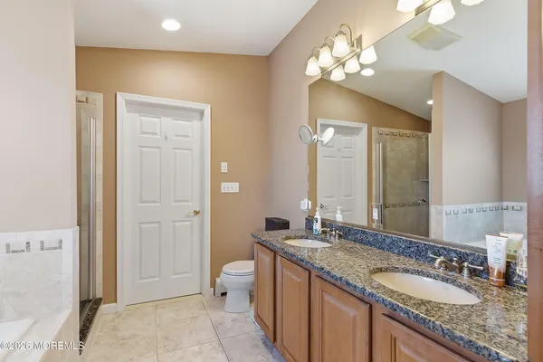 a bathroom with a granite countertop double vanity sink a mirror and a shower