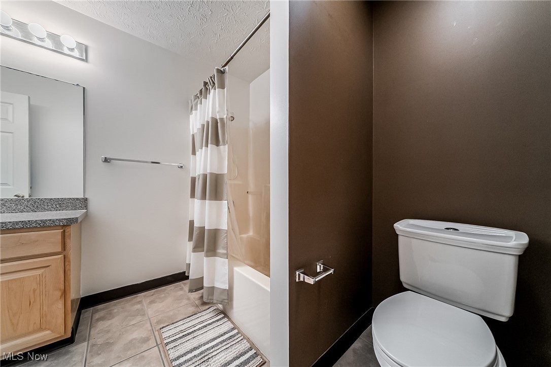 882 Overlook Ridge Drive Cleveland, OH 44109 - Photo 16 of 26 Full bath featuring a textured ceiling, vanity, tile patterned floors, and shower / tub combo with curtain