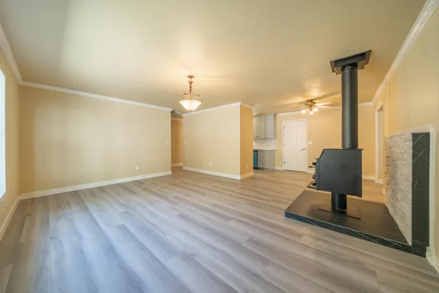 a view of an empty room with wooden floor and a ceiling fan