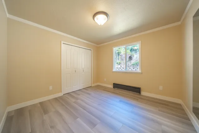 a view of an empty room with window and wooden floor