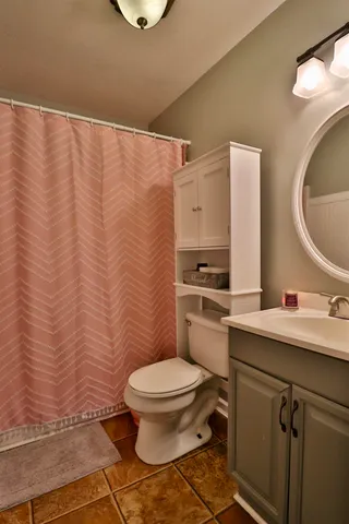 a bathroom with a toilet sink vanity and mirror