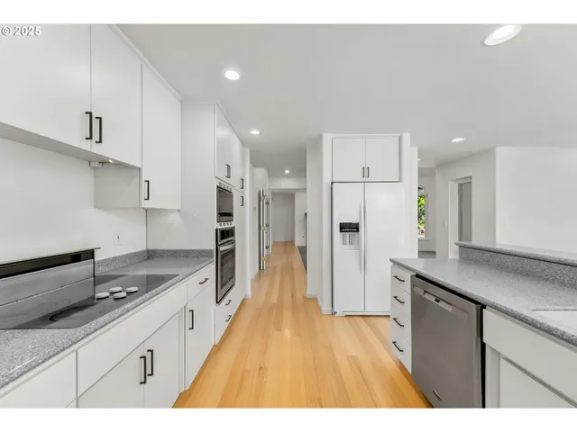 a large kitchen with stainless steel appliances kitchen island granite countertop a refrigerator and a sink