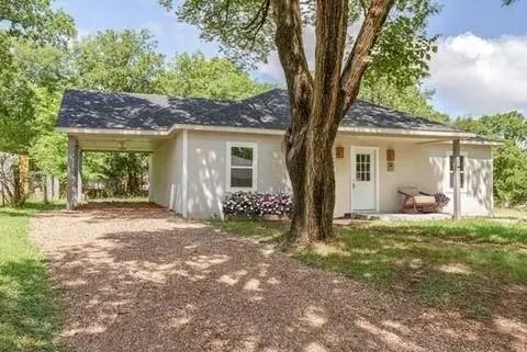 Back of house with driveway, a carport, and stucco siding