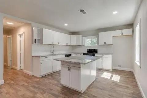 221 Braz Street Bonham, TX 75418 - Photo 3 of 12 Kitchen with white cabinetry, black range, light wood-style flooring, and recessed lighting