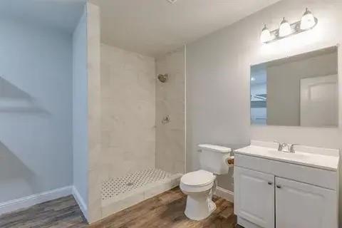 221 Braz Street Bonham, TX 75418 - Photo 9 of 12 Bathroom featuring vanity, dark wood-style floors, and a stall shower