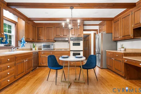 a kitchen with stainless steel appliances kitchen island granite countertop a refrigerator a stove a sink dishwasher and a dining table with wooden floor