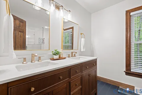 a bathroom with a granite countertop sink a large mirror a and window