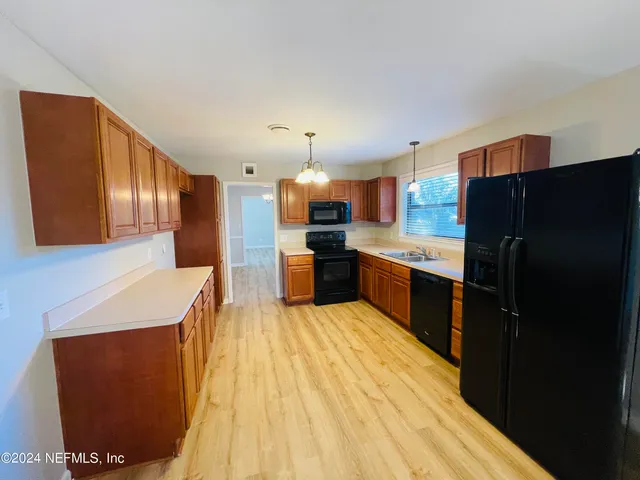 a large kitchen with stainless steel appliances kitchen island granite countertop a refrigerator and a sink