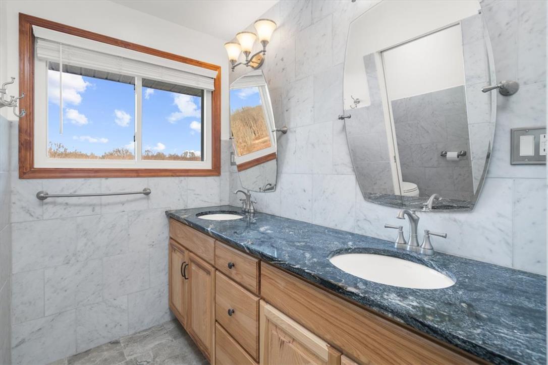 988 Hoch Road Danielsville, PA 18038 - Photo 6 of 29 A bathroom vanity boasts a luxurious double sink and marble-tiled walls.