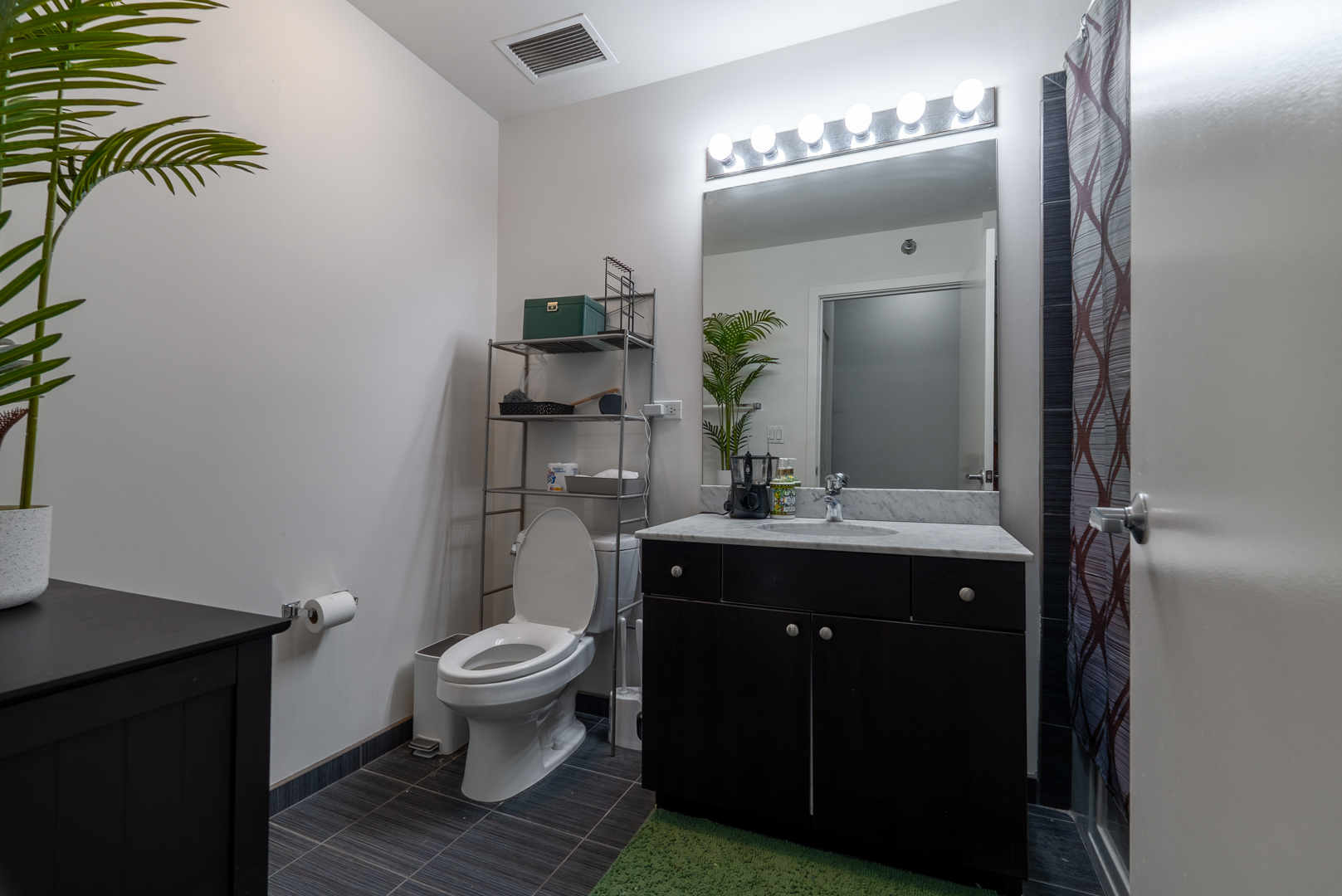 235 West Van Buren Street, Unit 1809 Chicago, IL 60607 - Photo 8 of 17 a bathroom with a granite countertop sink toilet and mirror