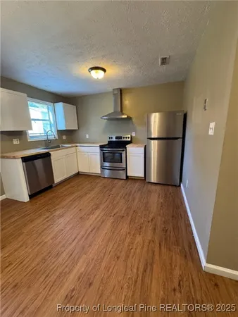 a kitchen with stainless steel appliances granite countertop a refrigerator a stove and a wooden floors