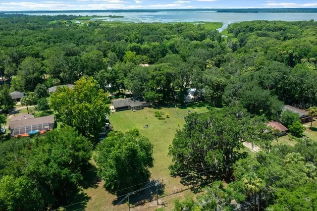 an aerial view of residential house with outdoor space and trees all around