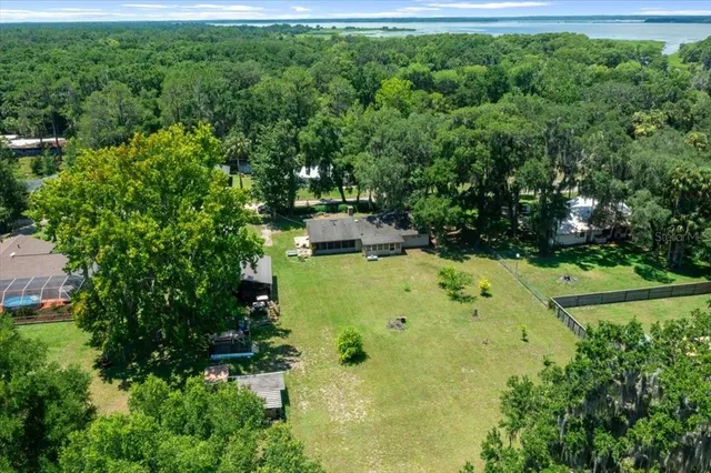 an aerial view of residential house with outdoor space and trees all around