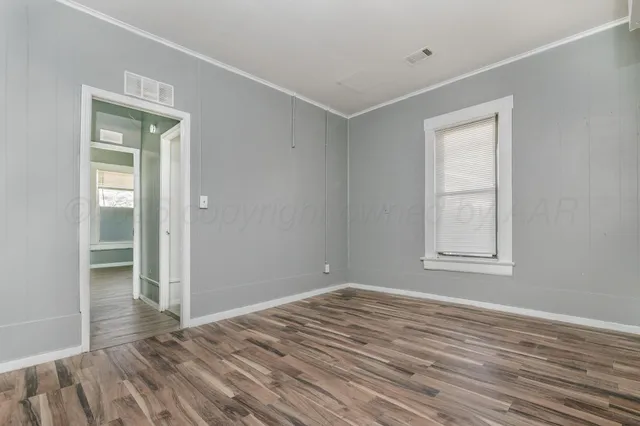 a view of empty room with wooden floor and fan