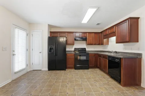 a kitchen with granite countertop a refrigerator and a stove top oven