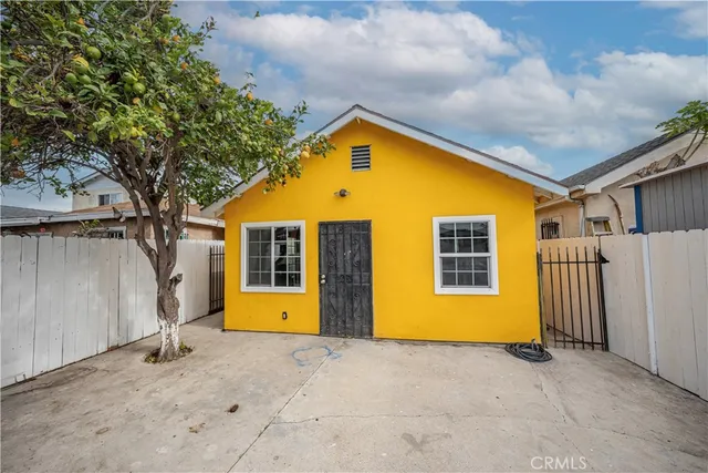 a view of a house with wooden fence and a tree