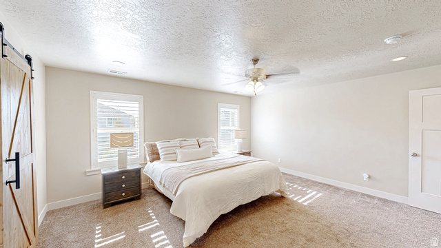 368 East 700 North Springville, UT 84663 - Photo 11 of 55 Bedroom featuring a barn door, a textured ceiling, light colored carpet, and a ceiling fan