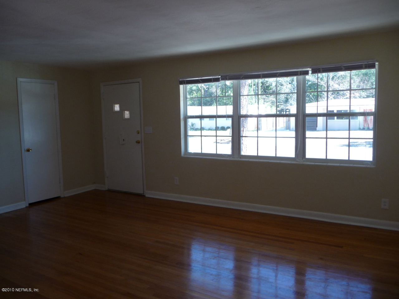 3384 Rogero Road Jacksonville, FL 32277 - Photo 4 of 17 a view of an empty room with wooden floor and a window
