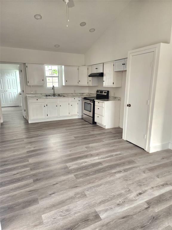 1178 Nob Hill Road Quinlan, TX 75474 - Photo 5 of 13 Kitchen with stainless steel electric range oven, under cabinet range hood, vaulted ceiling, white cabinetry, and light wood-style flooring