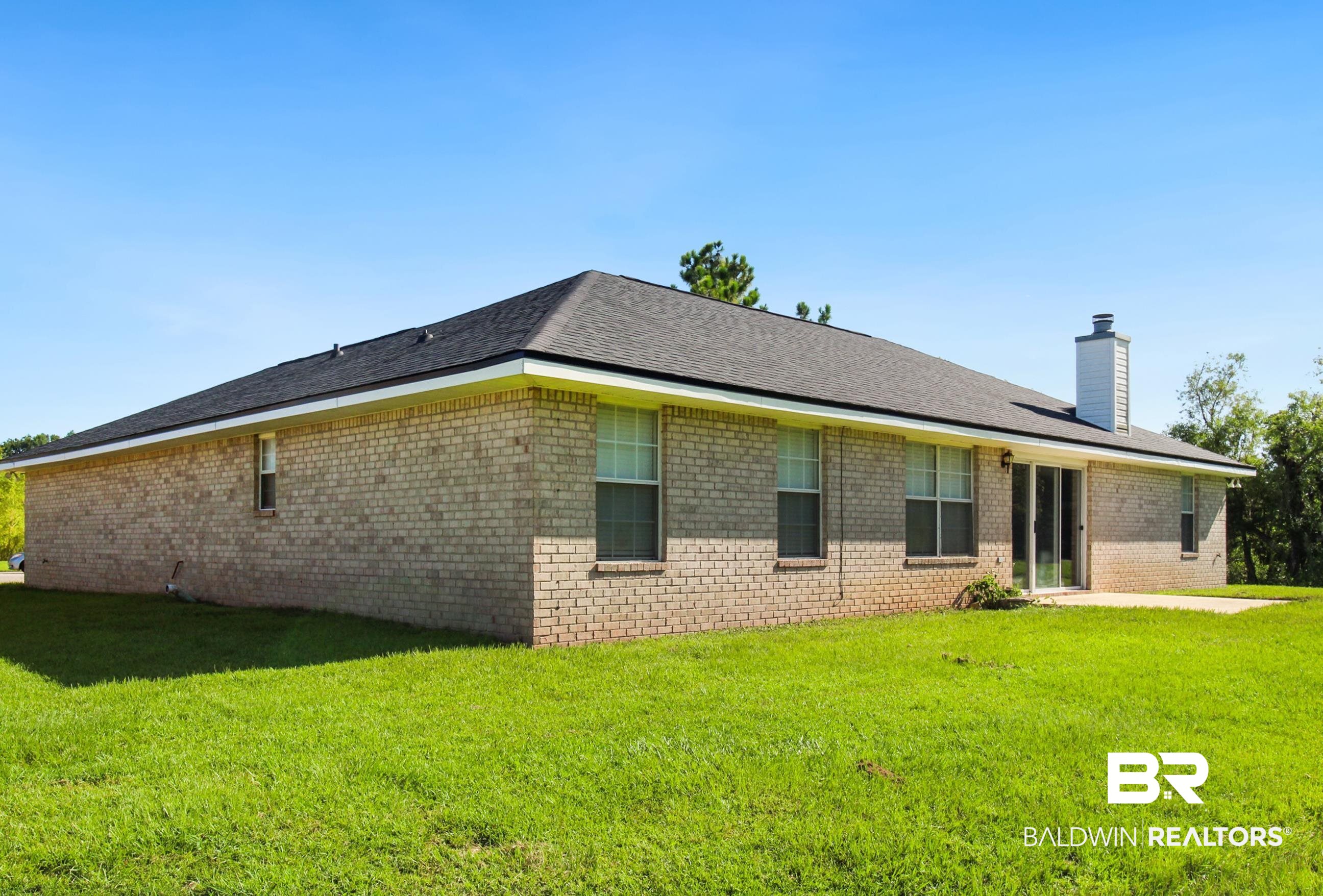 14750 Pawnee Court Foley, AL 36535 - Photo 33 of 34 Back of house featuring a yard, brick siding, a chimney, and a patio area