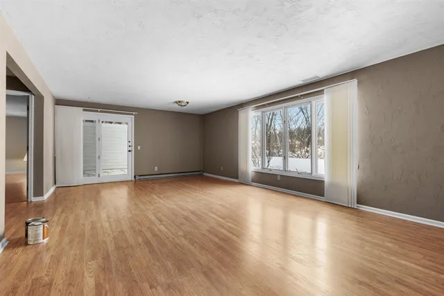 a view of an empty room with wooden floor and a window