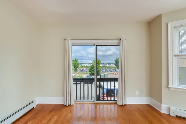 a view of an empty room with a window and wooden floor