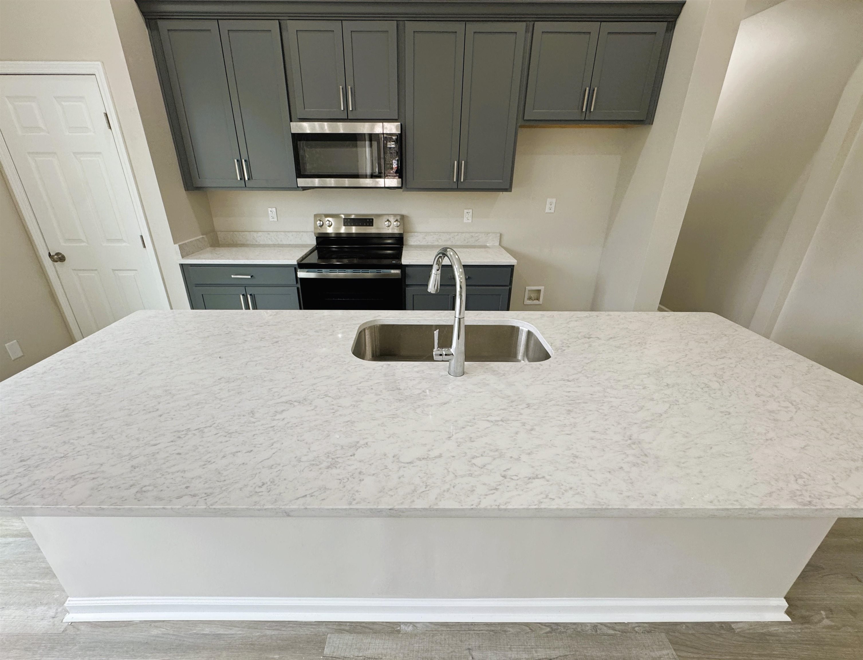 547 Berclair Road, Unit 101 Memphis, TN 38122 - Photo 6 of 19 Kitchen with stainless steel appliances, an island with sink, wood finished floors, light stone counters, and gray cabinetry