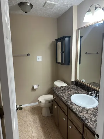 a bathroom with a granite countertop sink a toilet a mirror and shower