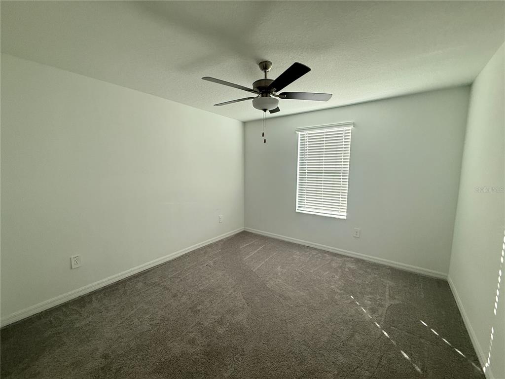 2881 Silver Scallop Loop Wimauma, FL 33598 - Photo 14 of 17 an empty room with a ceiling fan and a window