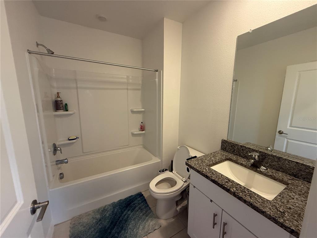 2881 Silver Scallop Loop Wimauma, FL 33598 - Photo 6 of 17 a bathroom with a granite countertop toilet a sink and a bathtub