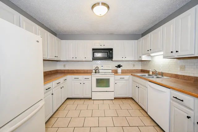 a kitchen with granite countertop white cabinets and stainless steel appliances