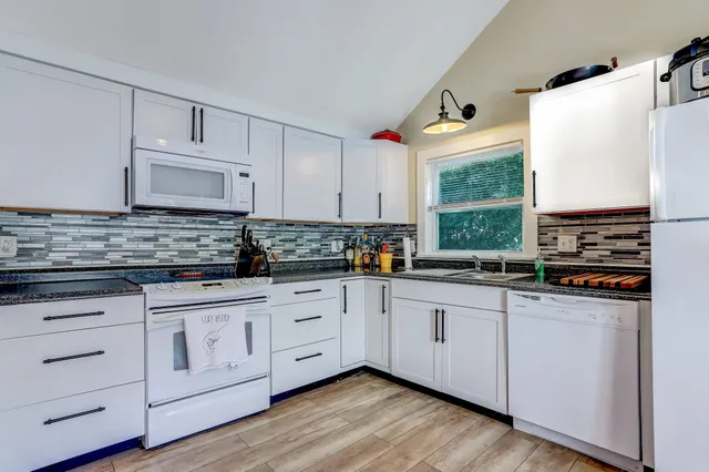 a kitchen with stainless steel appliances granite countertop a sink a stove and cabinets