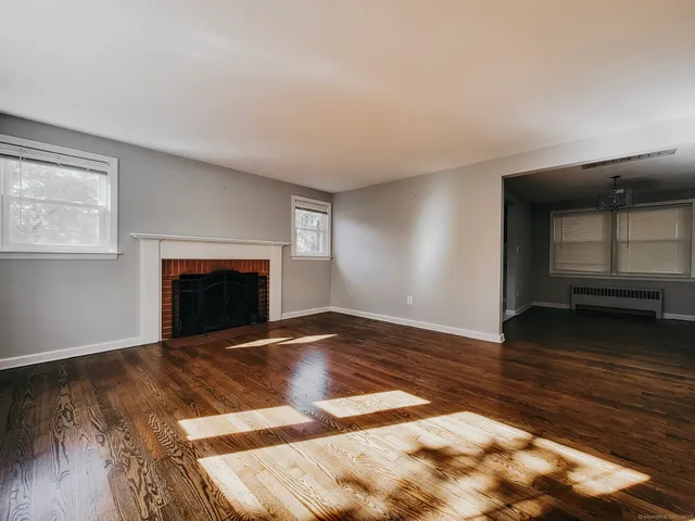 a view of empty room with wooden floor and fireplace