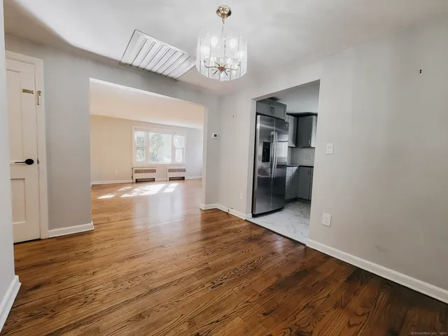 a view of an empty room with kitchen and window
