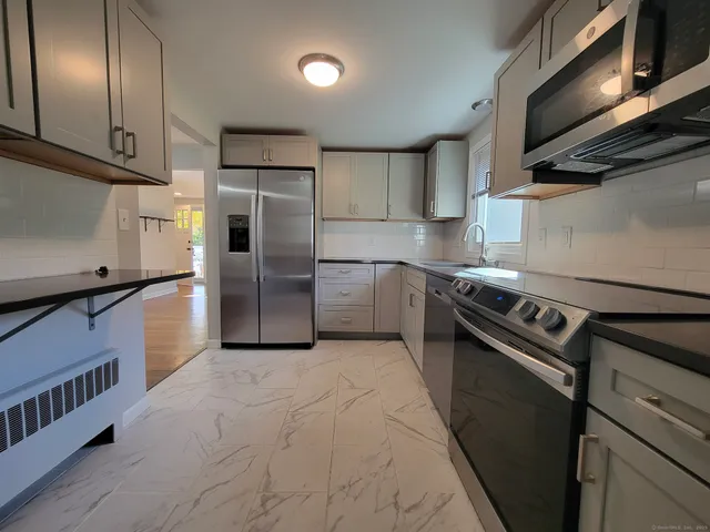 a kitchen with stainless steel appliances granite countertop a refrigerator a stove and a sink with wooden floor