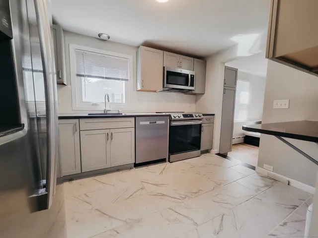 a kitchen with stainless steel appliances granite countertop a sink and a stove top oven with wooden floor