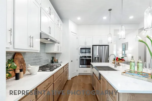 a kitchen with stainless steel appliances kitchen island granite countertop a lot of counter space and wooden floors