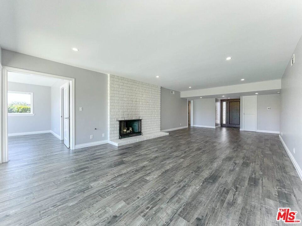 an empty room with wooden floor and fireplace