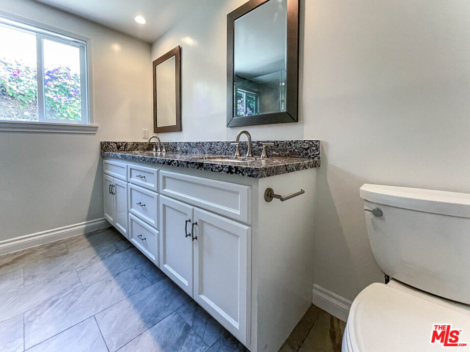 3824 Surfwood Road Malibu, CA 90265 - Photo 30 of 36 a bathroom with a granite countertop toilet sink and mirror