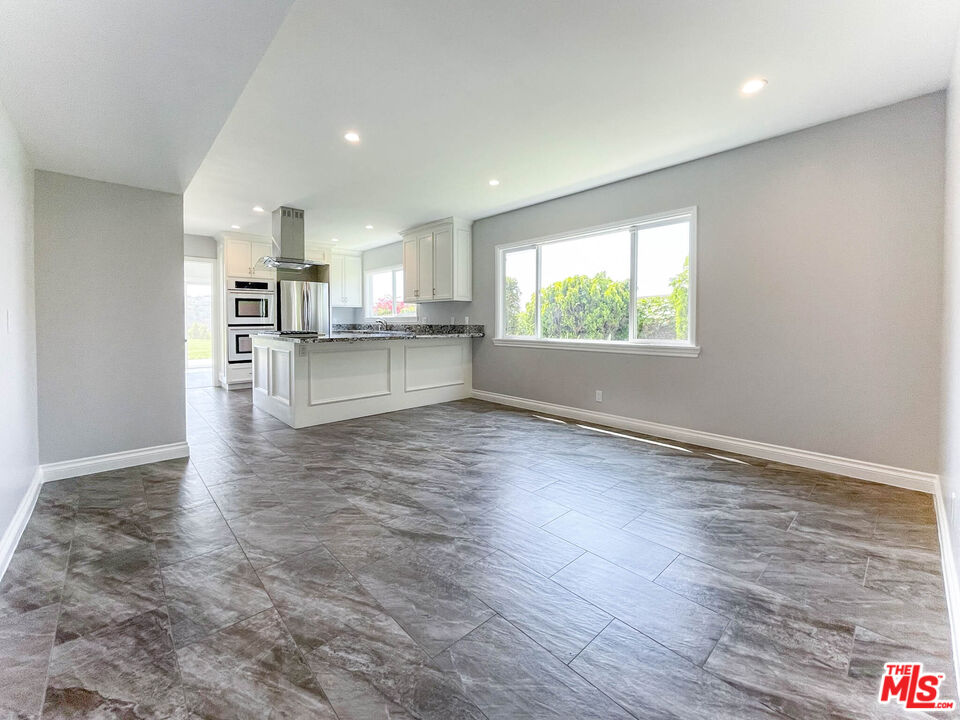 3824 Surfwood Road Malibu, CA 90265 - Photo 5 of 36 an empty room with wooden floor and a kitchen