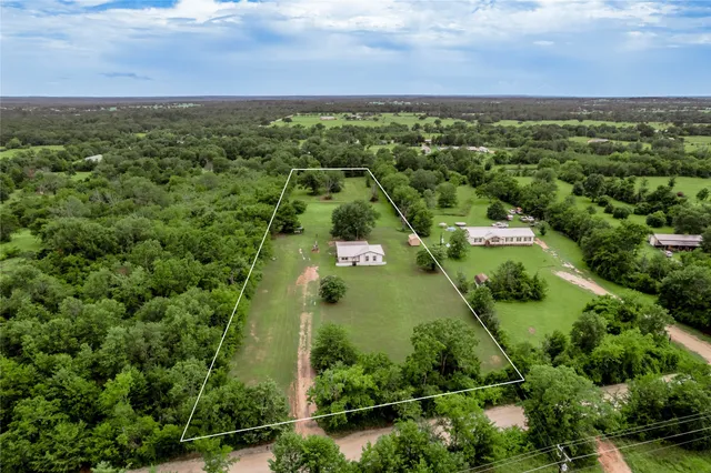 an aerial view of residential houses with outdoor space and trees