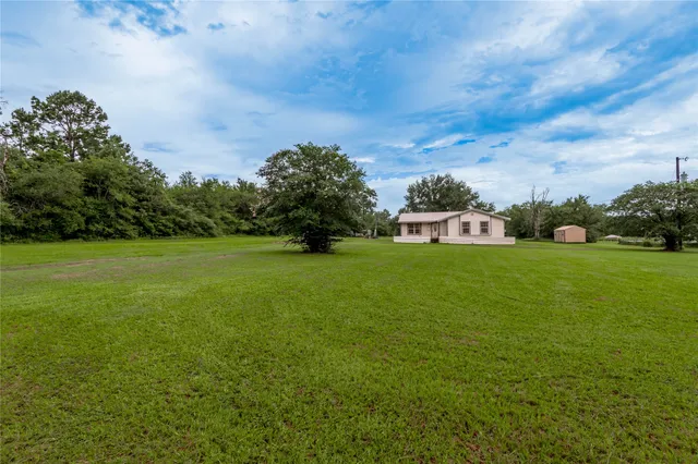 a view of a green field with house in the background