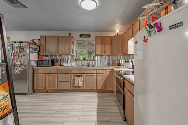 a kitchen with stainless steel appliances granite countertop a refrigerator sink and wooden cabinets