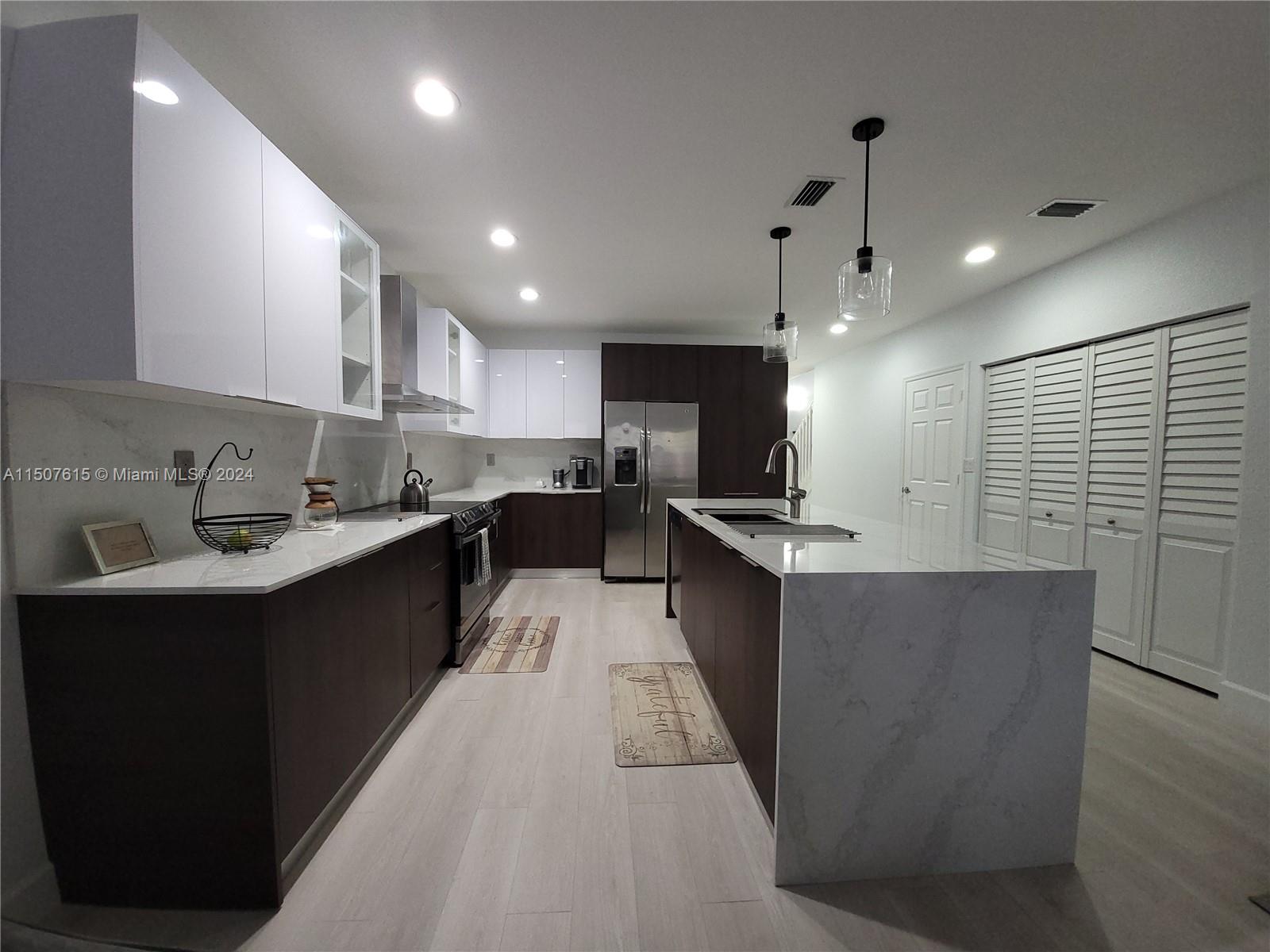 293 Las Brisas Circle Sunrise, FL 33326 - Photo 13 of 69 a large kitchen with stainless steel appliances kitchen island a large counter top a stove a sink a refrigerator and a cabinets